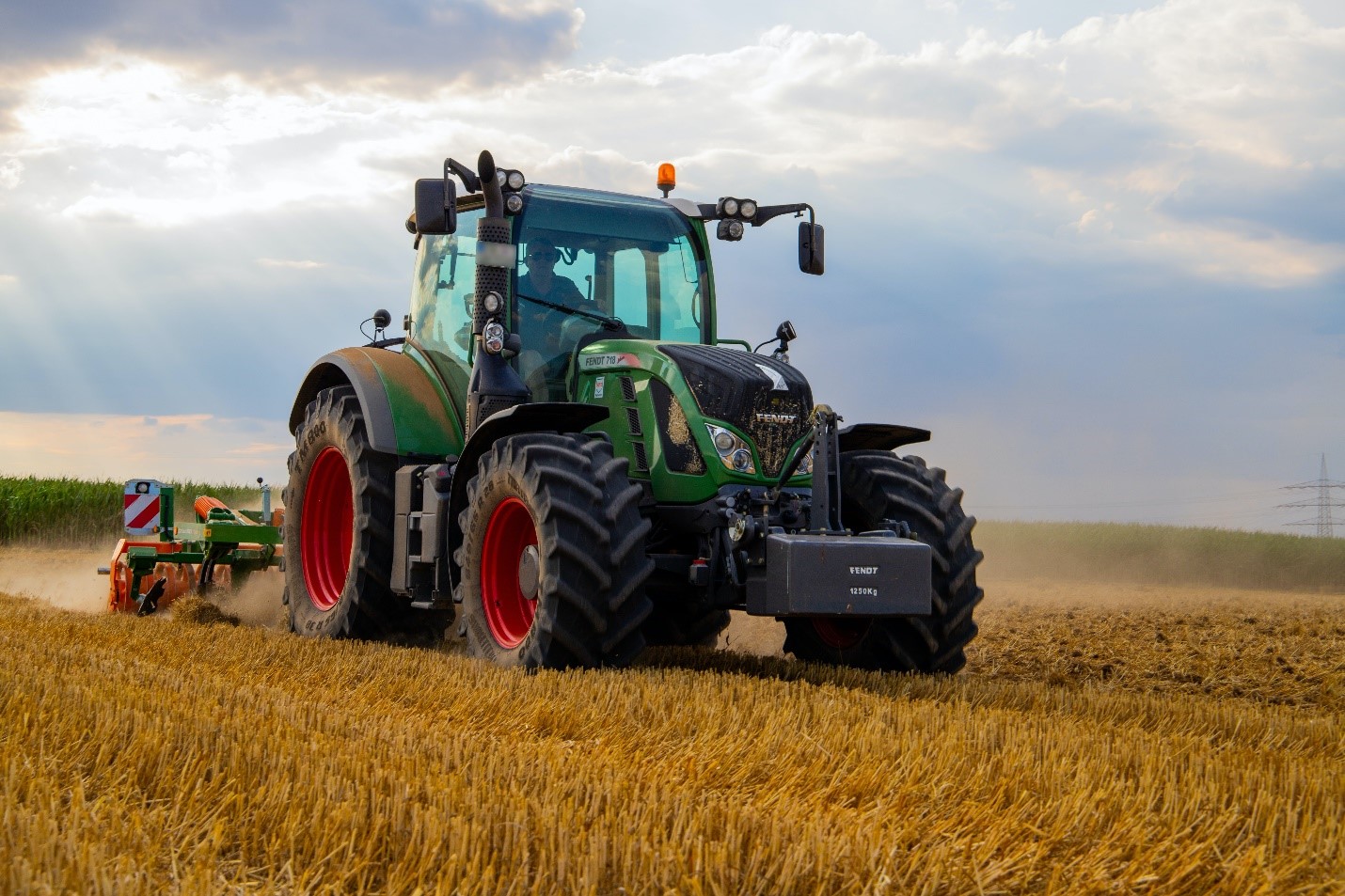 Green tractor harvesting field