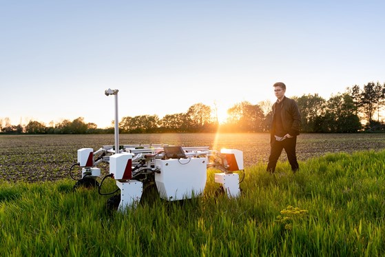 Man walking through field with farm robot