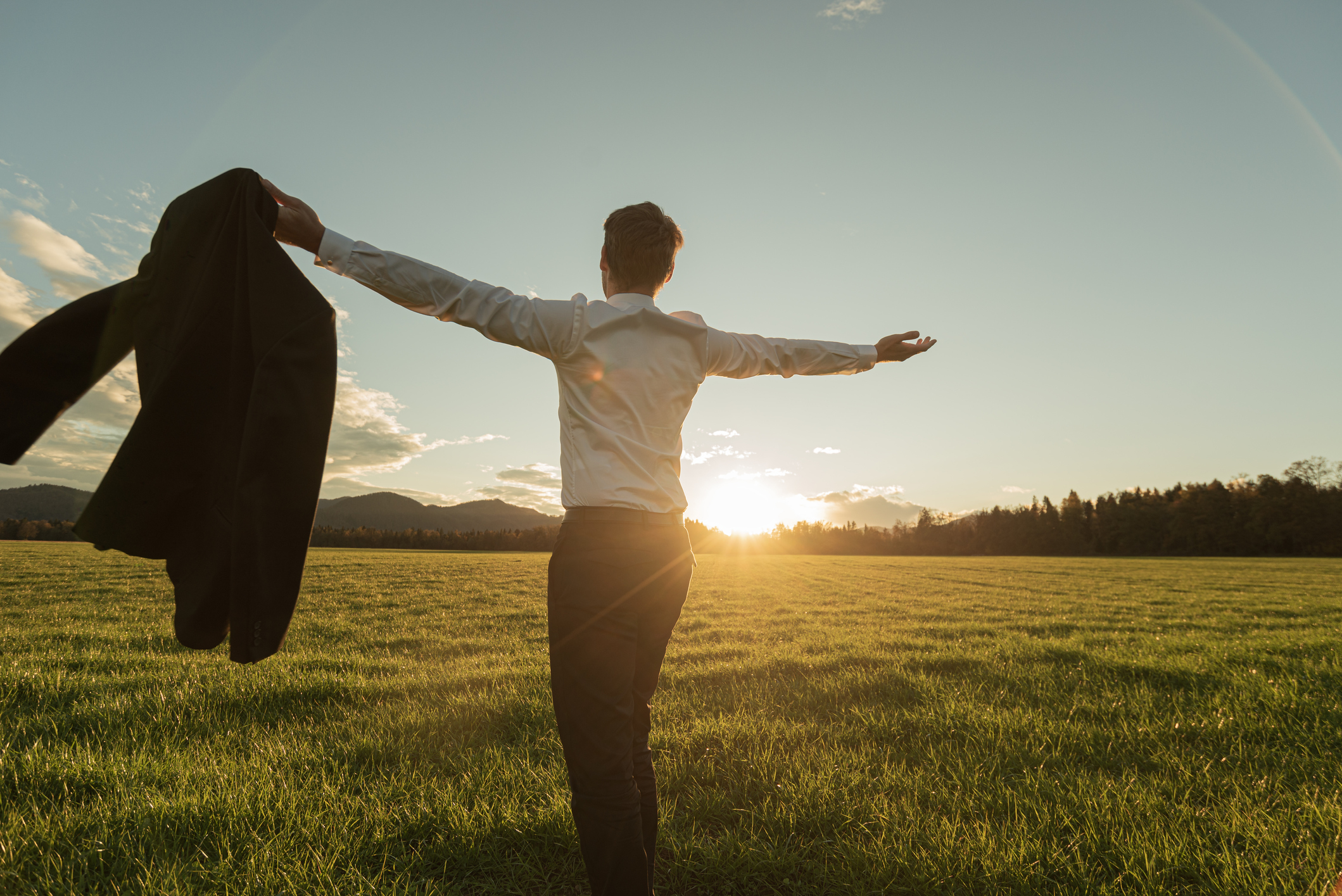 Man in a suit in a field at sunset