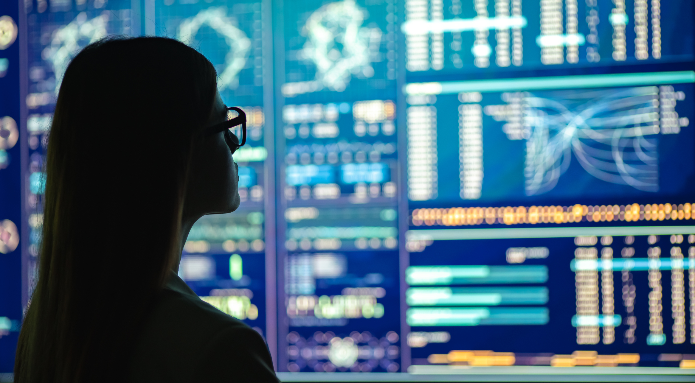 Businesswoman in glasses standing near the screens displaying big data