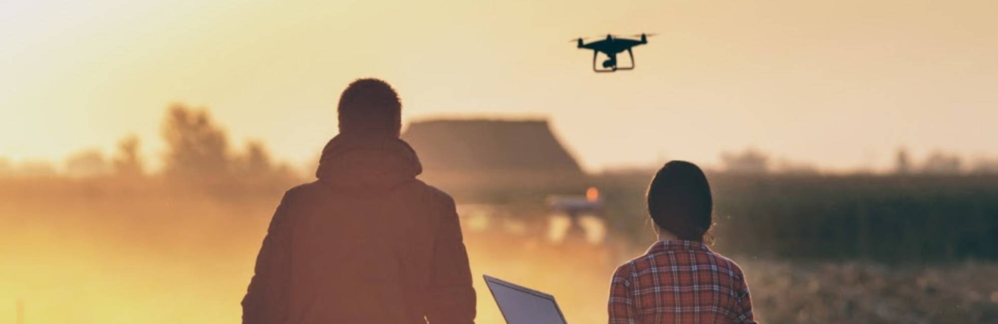Woman and man farmer walking in field with a drone